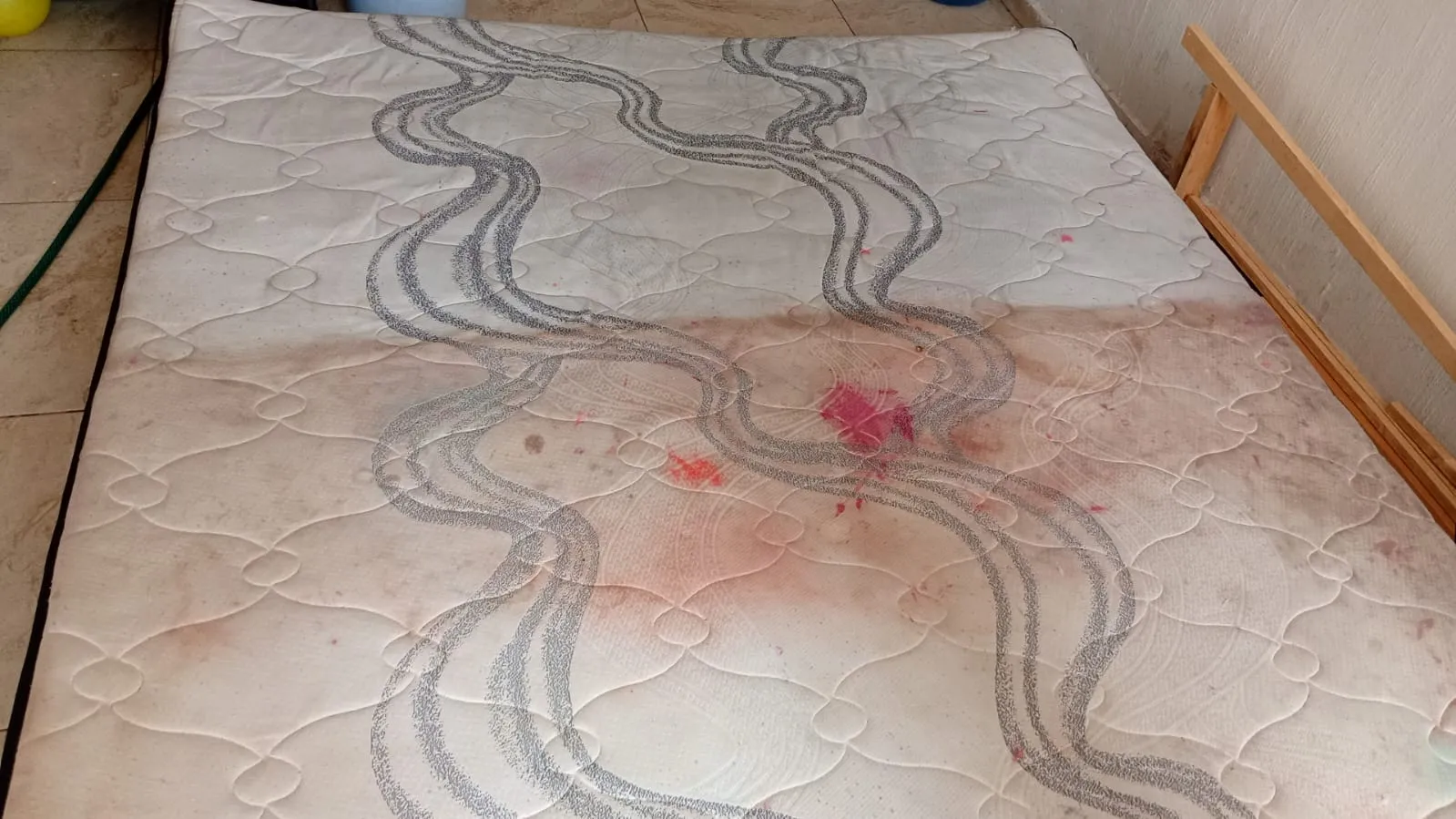 Colchón con manchas de sangre y humedad, mitad lavada mitad sin lavar