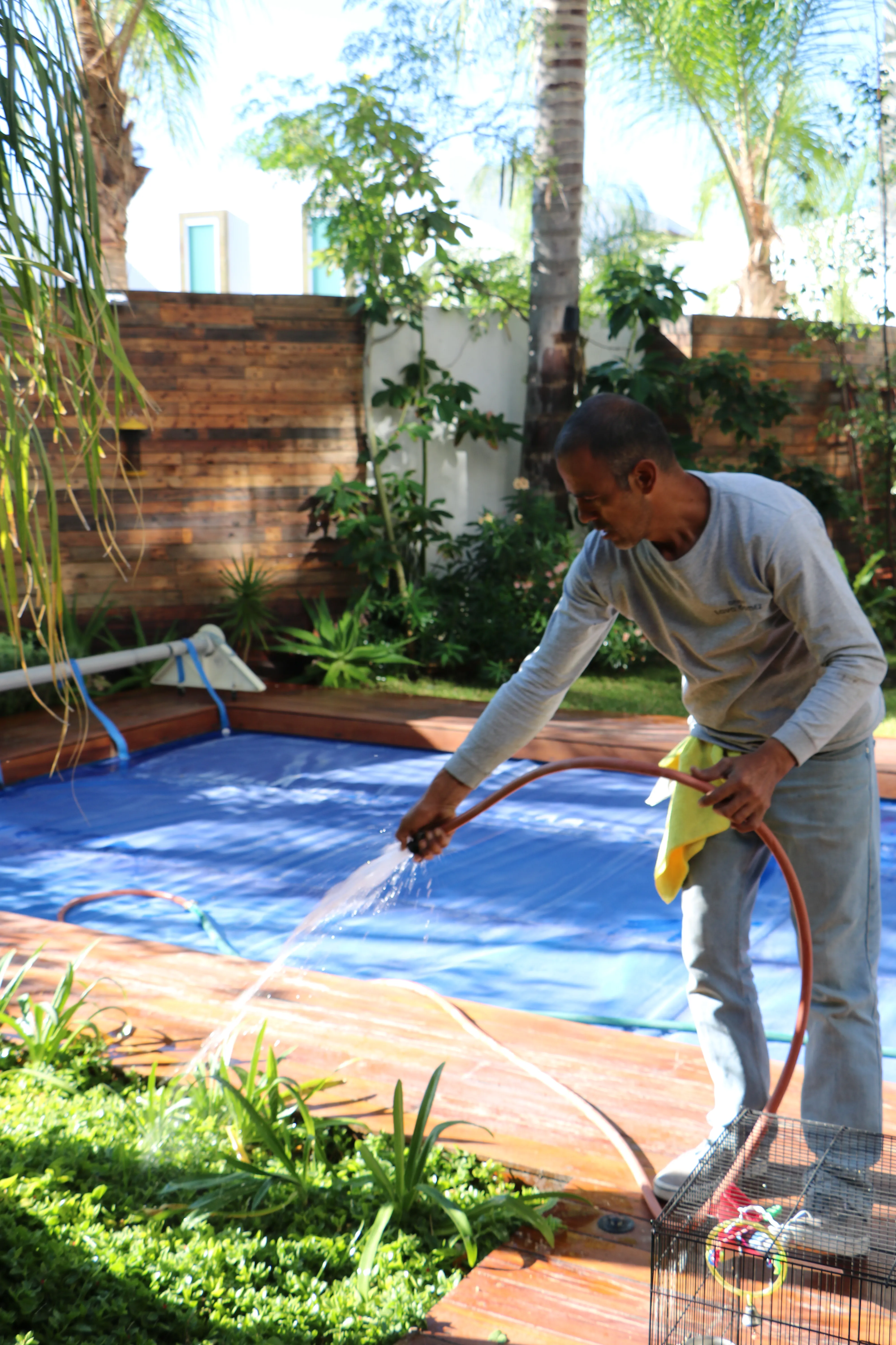 Persona lavando con manguera una terraza con jardín