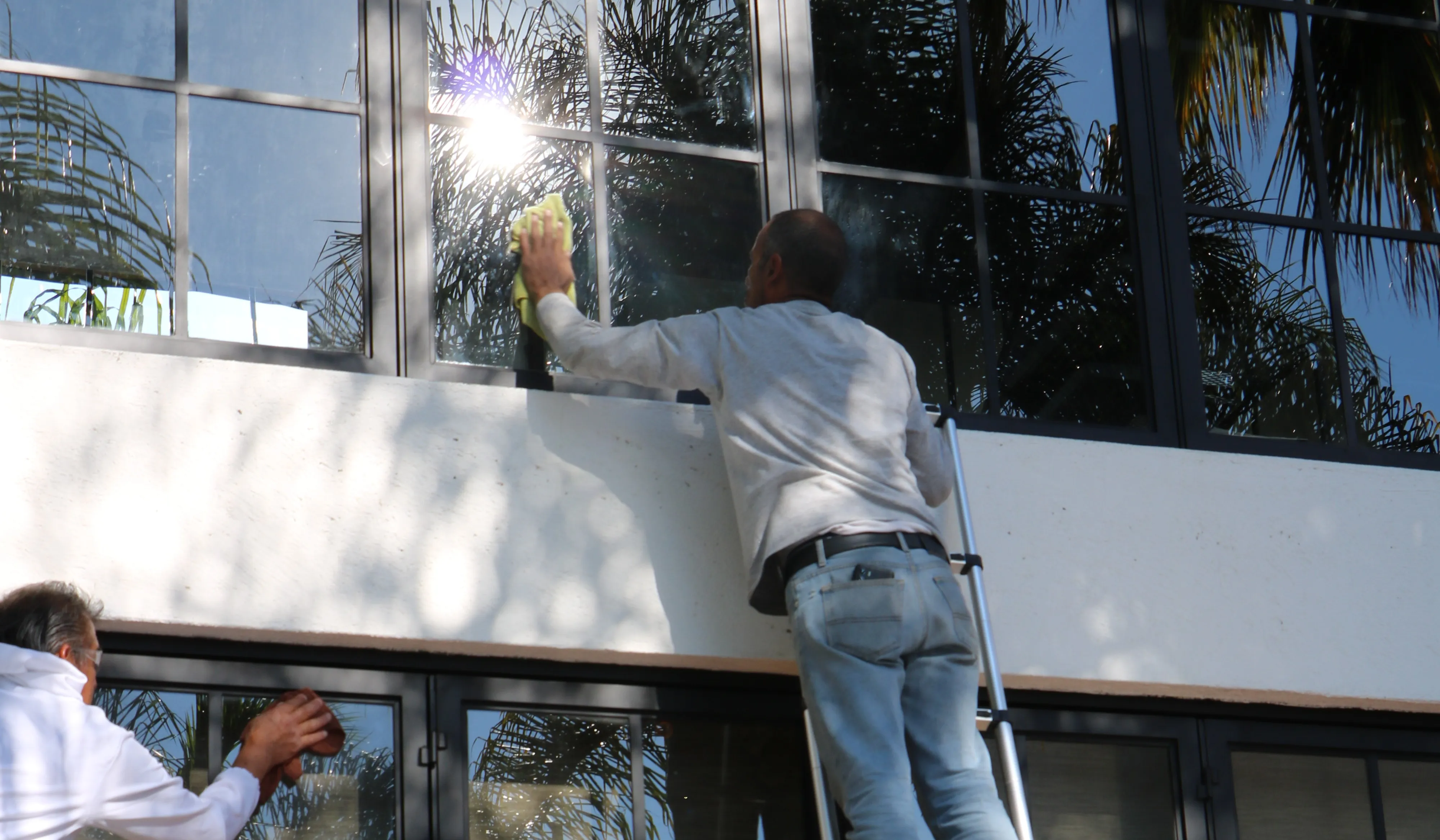 Técnicos limpiando un ventanal grande con luz natural